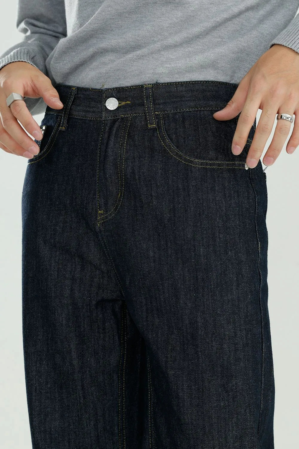 Dark wash wide-leg denim jeans with relaxed fit and yellow stitching.