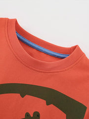 Coral cotton toddler t-shirt with playful green crocodile graphic and blue trim neckline.