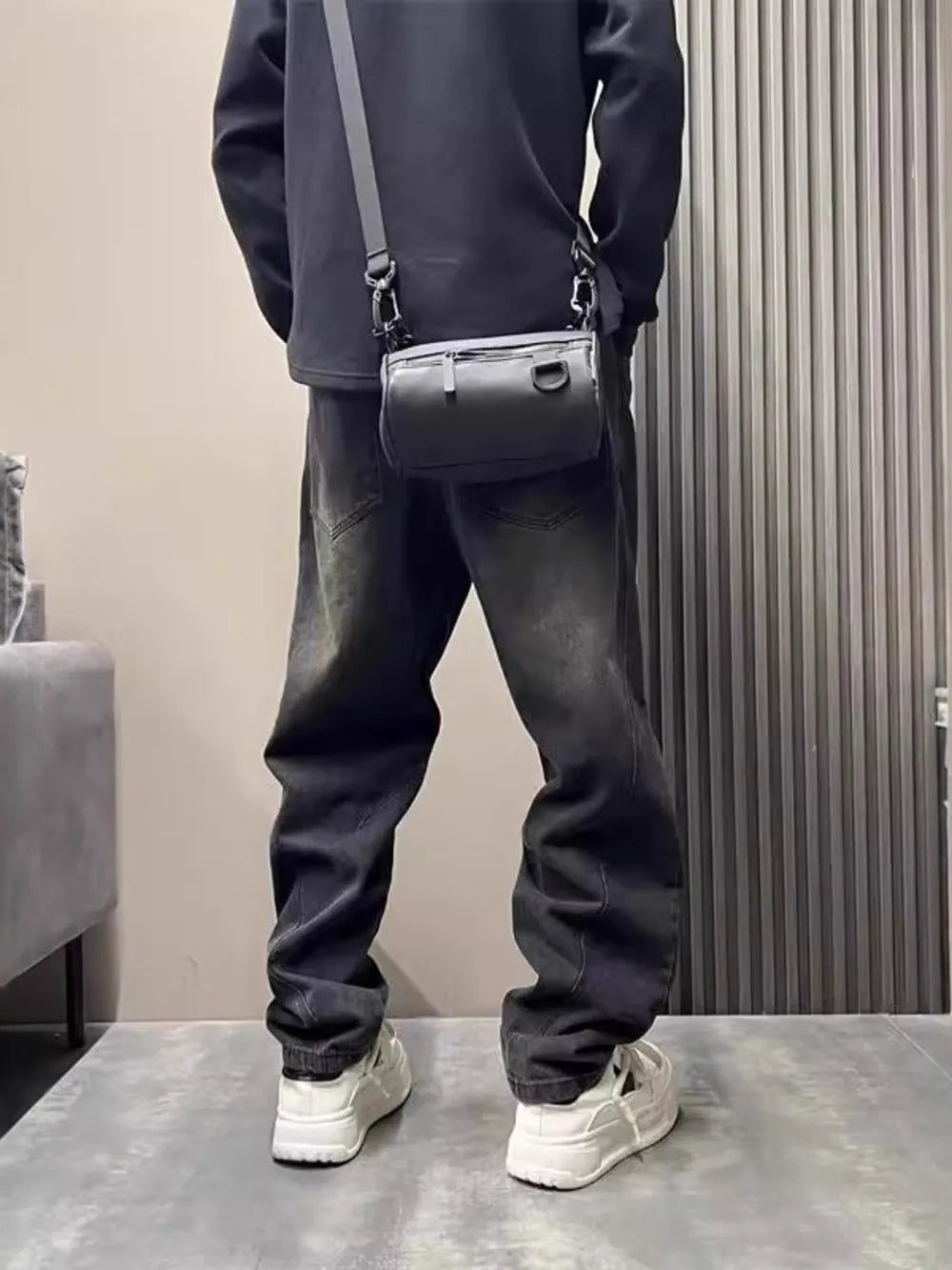 Oversized washed black men's jeans with tapered cuffs and a crossbody bag.