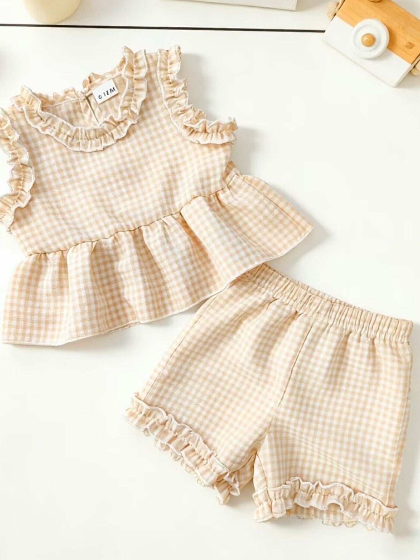 Children's beige gingham ruffle two-piece set with peplum top and shorts.