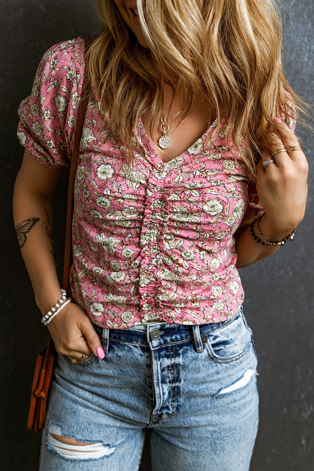 Floral ruched bodice puff sleeve top with v-neck and short sleeves, styled with denim shorts.