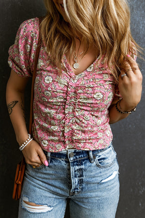 Floral ruched bodice puff sleeve top with v-neck and short sleeves, styled with denim shorts.