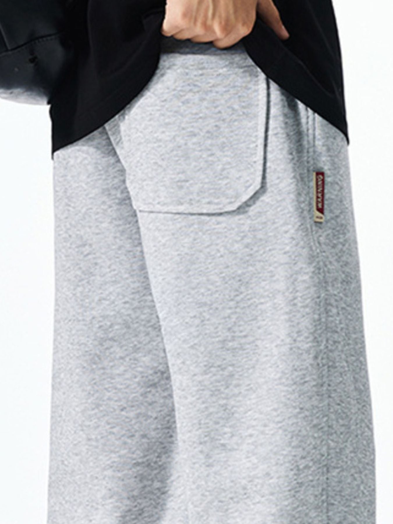 Men's grey casual drawstring sweatpants with a back pocket detail and branded tag.