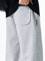 Men's grey casual drawstring sweatpants with a back pocket detail and branded tag.