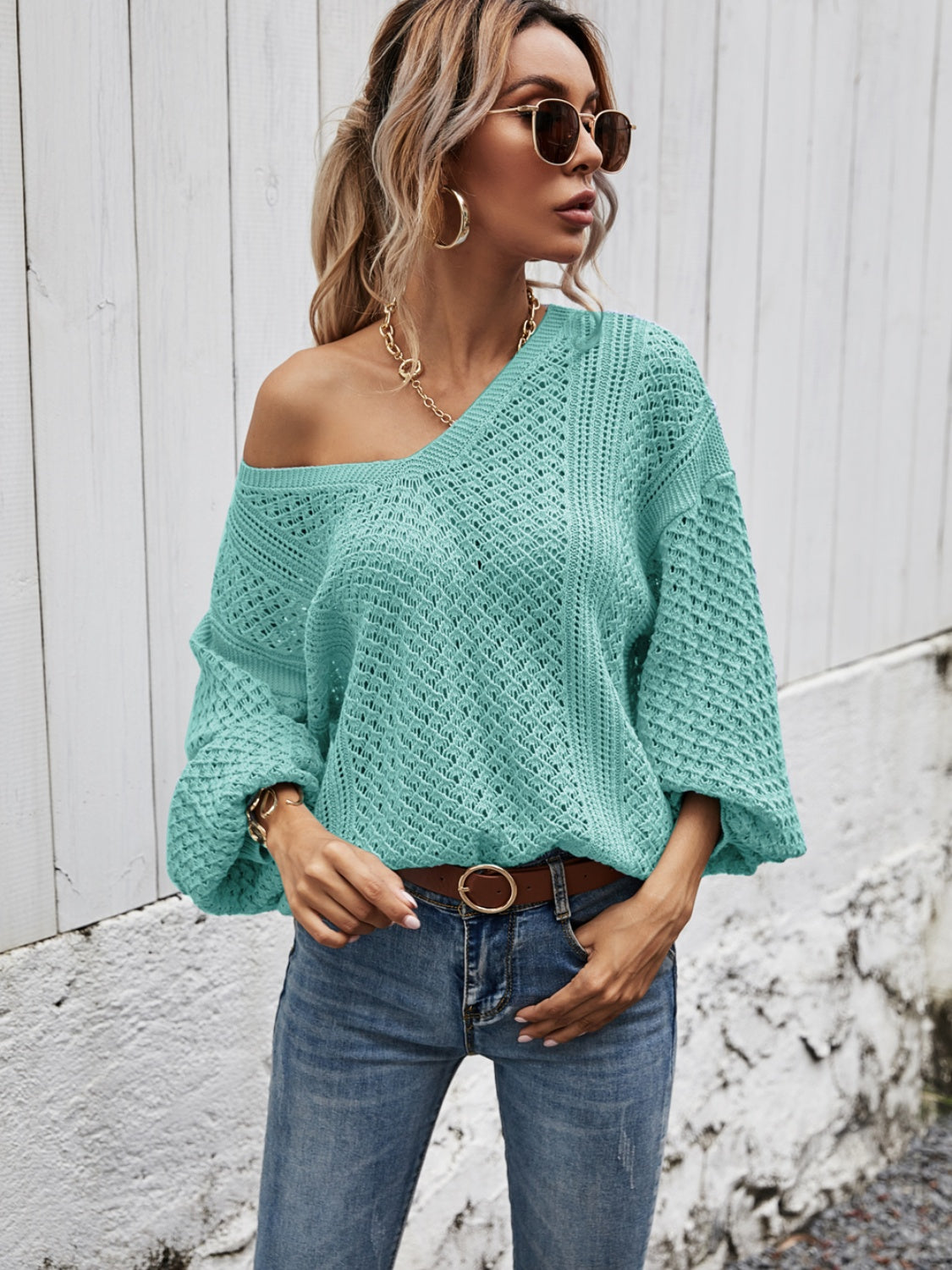Teal open-knit sweater with balloon sleeves and a v-neck, styled with jeans.