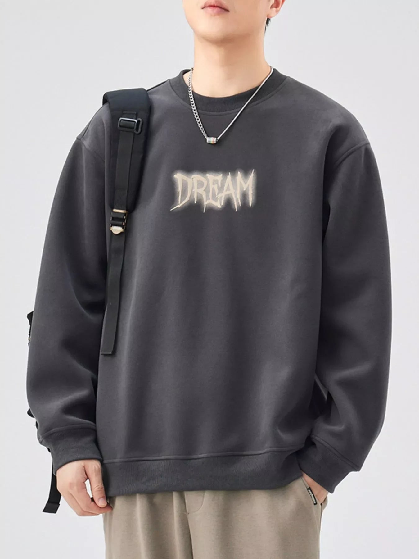 Oversized dark gray crew-neck sweatshirt with a distressed "DREAM" graphic on the front.