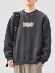 Oversized dark gray crew-neck sweatshirt with a distressed "DREAM" graphic on the front.
