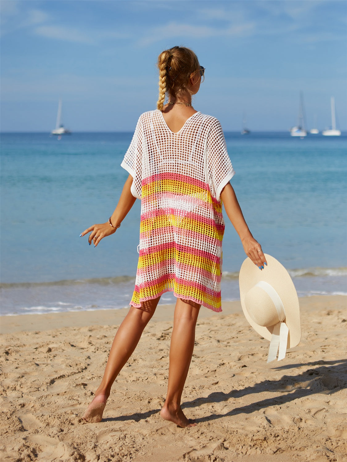 Crochet beach poncho with rainbow stripes in pink, yellow, and white.