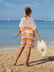 Crochet beach poncho with rainbow stripes in pink, yellow, and white.