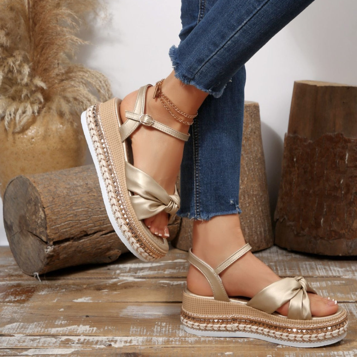 Gold bow knot wedge sandals with ankle buckle and braided trim detail.