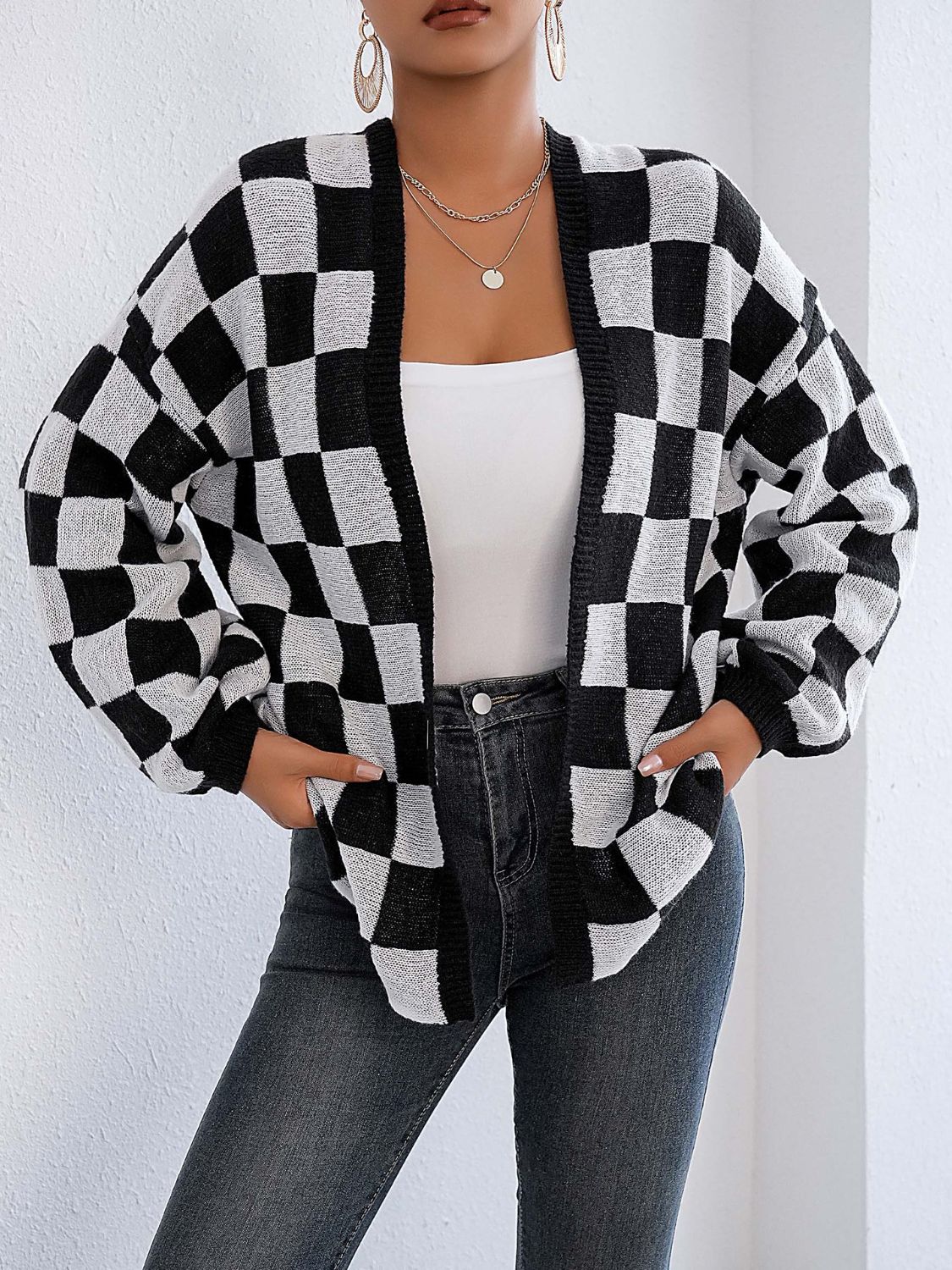 Checkerboard knit cardigan in black and white with balloon sleeves and open front.