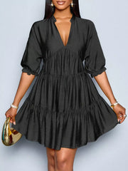 Black tiered dress with notched V-neck, puff sleeves, and ruffled cuffs.