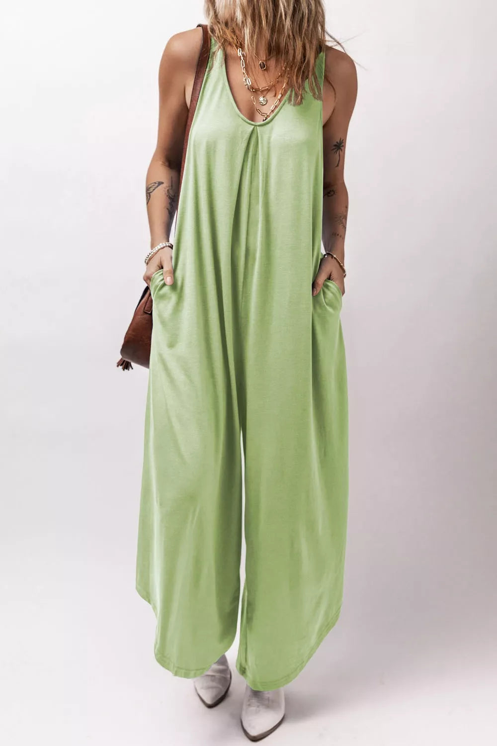 Sleeveless wide-leg romper in light green with V-neck, pleats, and pockets.