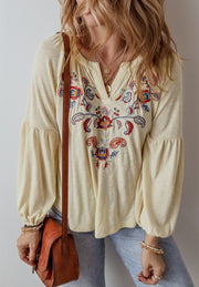 Pastel yellow blouse with embroidered floral detail and poet sleeves.