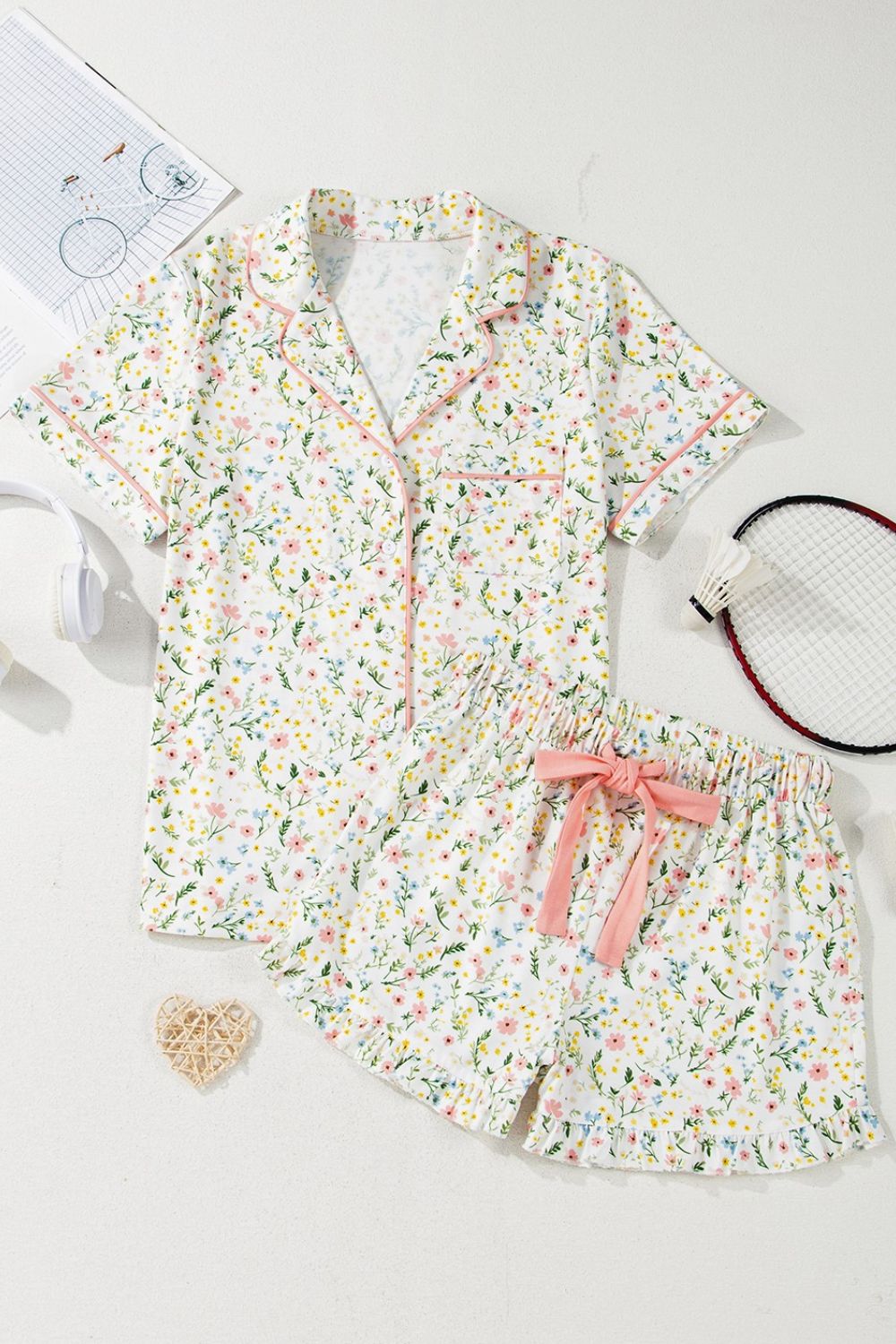 Floral print pajama set with pink trim, button-up top and ruffled shorts with bow.