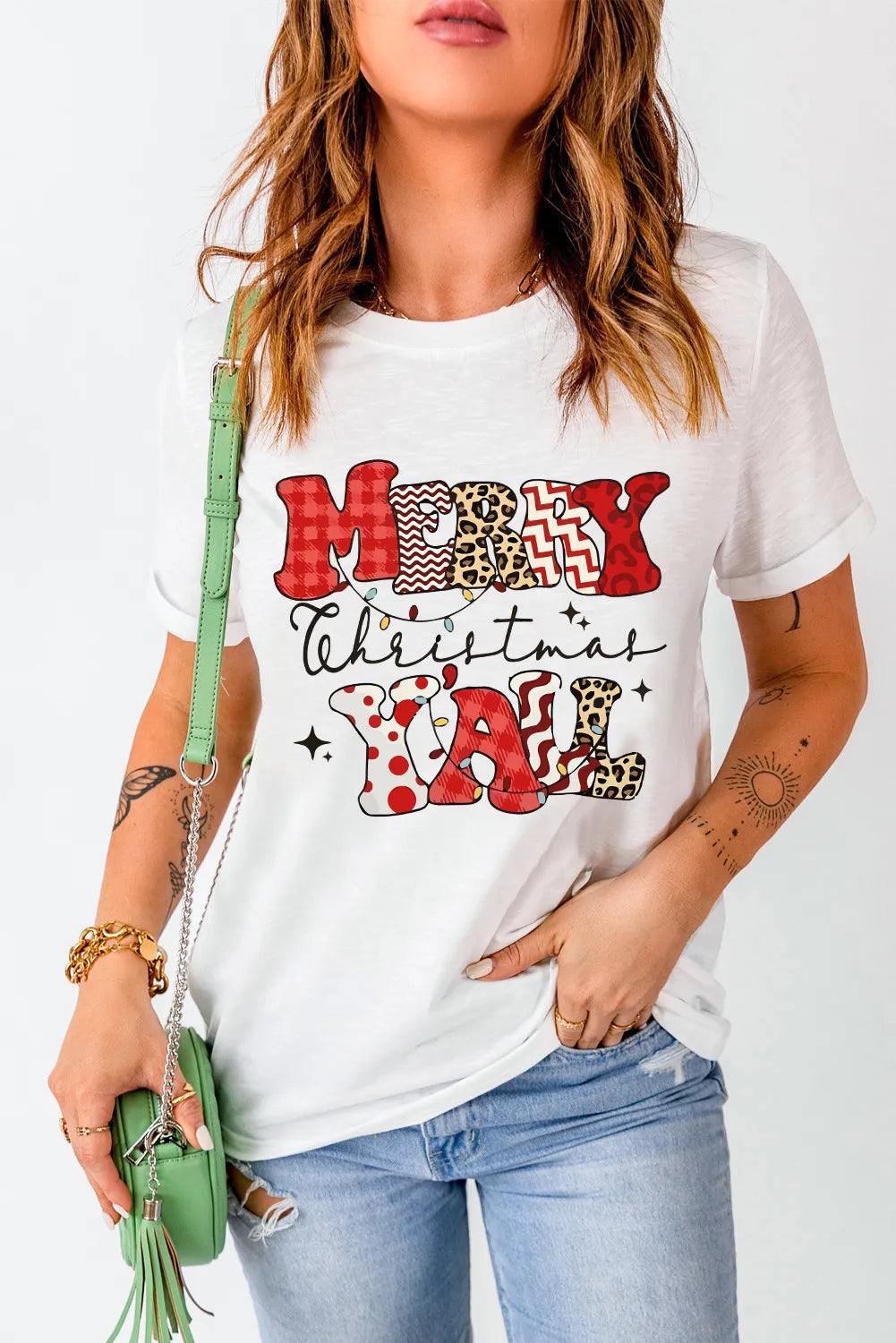 White graphic t-shirt with Merry Christmas Y'all text in patchwork patterns and string lights.