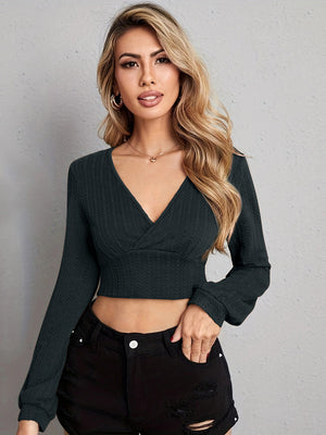 Textured wrap-front crop top in black with long sleeves and a deep V-neck.