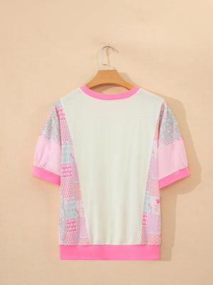 Maternity t-shirt with patchwork floral print sleeves, crew neck, and pink trim.