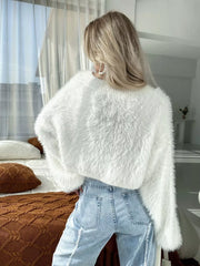 White fluffy knit cropped cardigan with crew neck and long sleeves, styled with light wash jeans.