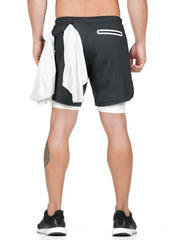 Black layered performance shorts with white built-in compression shorts and a white towel tucked into the waistband.