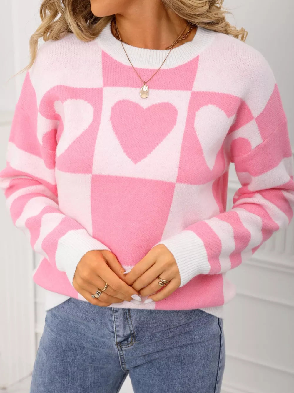 Blush pink and white checkerboard heart knit sweater with crew neck and long sleeves.