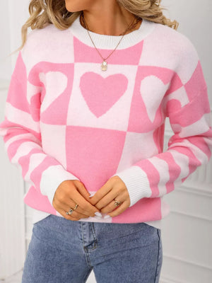 Blush pink and white checkerboard heart knit sweater with crew neck and long sleeves.