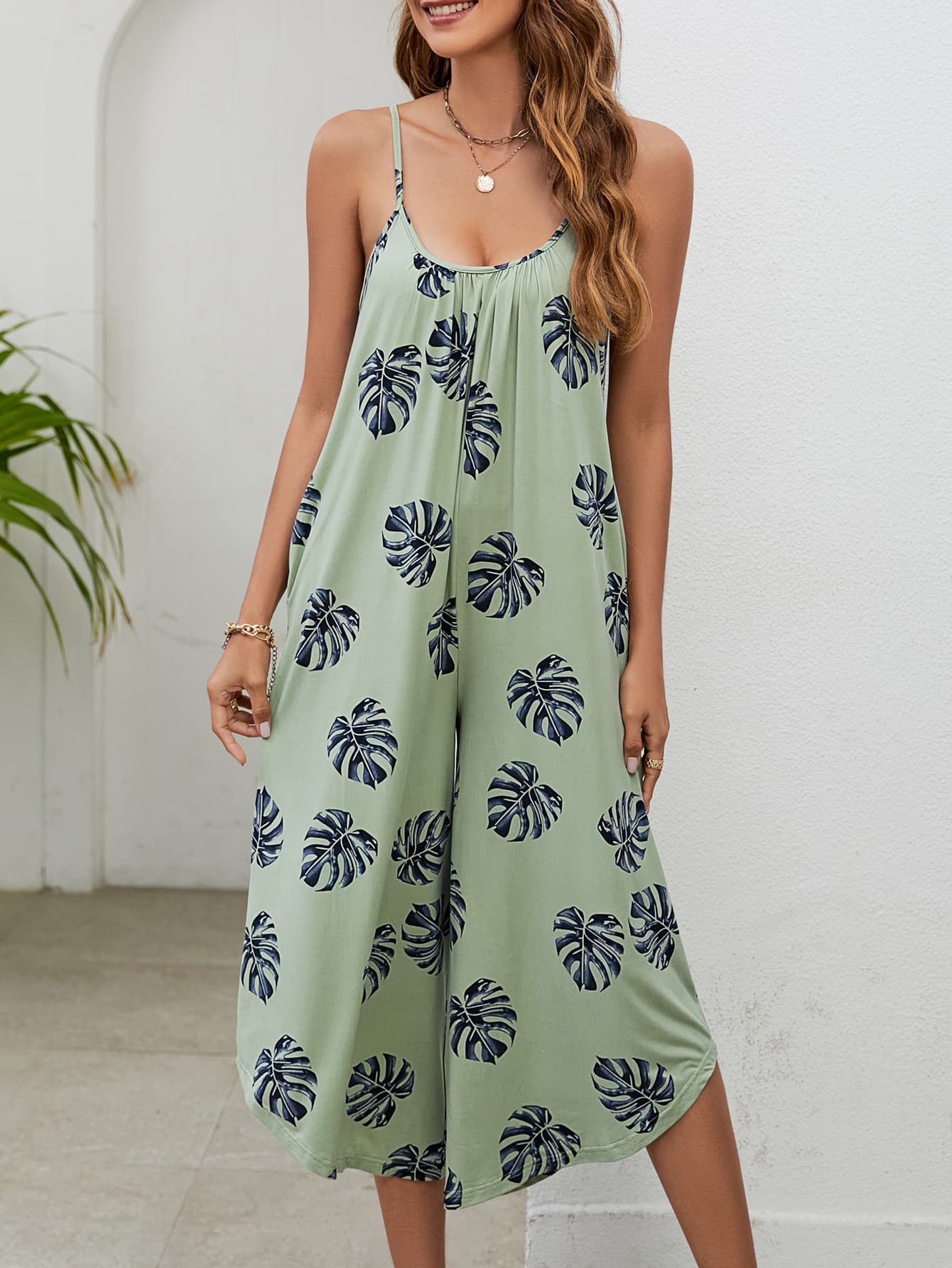 Sage green culotte jumpsuit with monstera print, gathered bust and spaghetti straps.