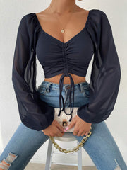 Black ruched bodice puff sleeve crop top with drawstring detail and sheer sleeves.