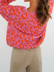 Vibrant leopard print tie-front cardigan in pink and orange with a crew neck.