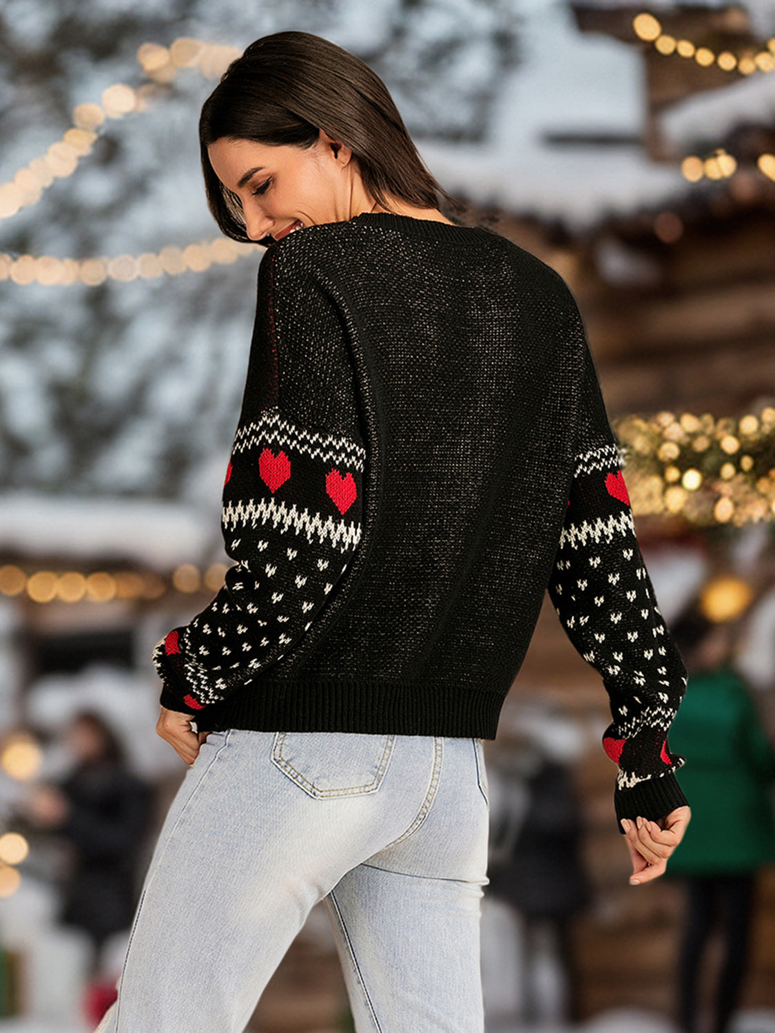 Black cotton sweater with round neck and red heart pattern on sleeves.
