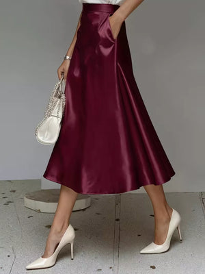 Wine red satin A-line skirt with pockets, shown with white heels and a white handbag.