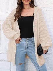 Tan balloon sleeve cardigan with pearl buttons and open front, styled with jeans.