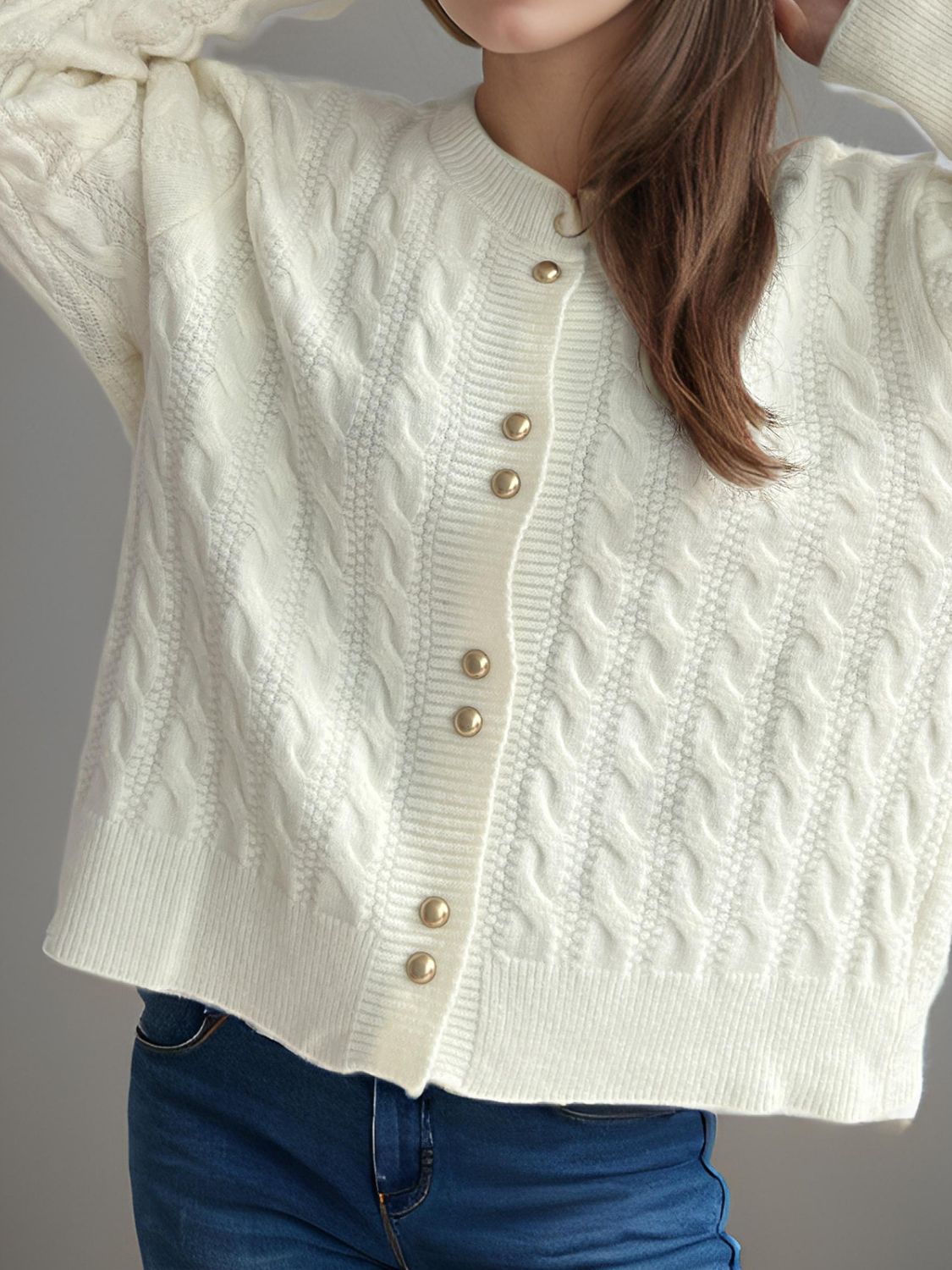 White cable knit acrylic cardigan with puff sleeves and gold buttons.