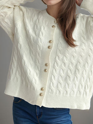 White cable knit acrylic cardigan with puff sleeves and gold buttons.