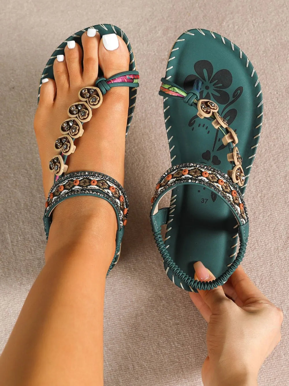 Dark green embellished thong sandals with floral detail and beaded ankle strap.