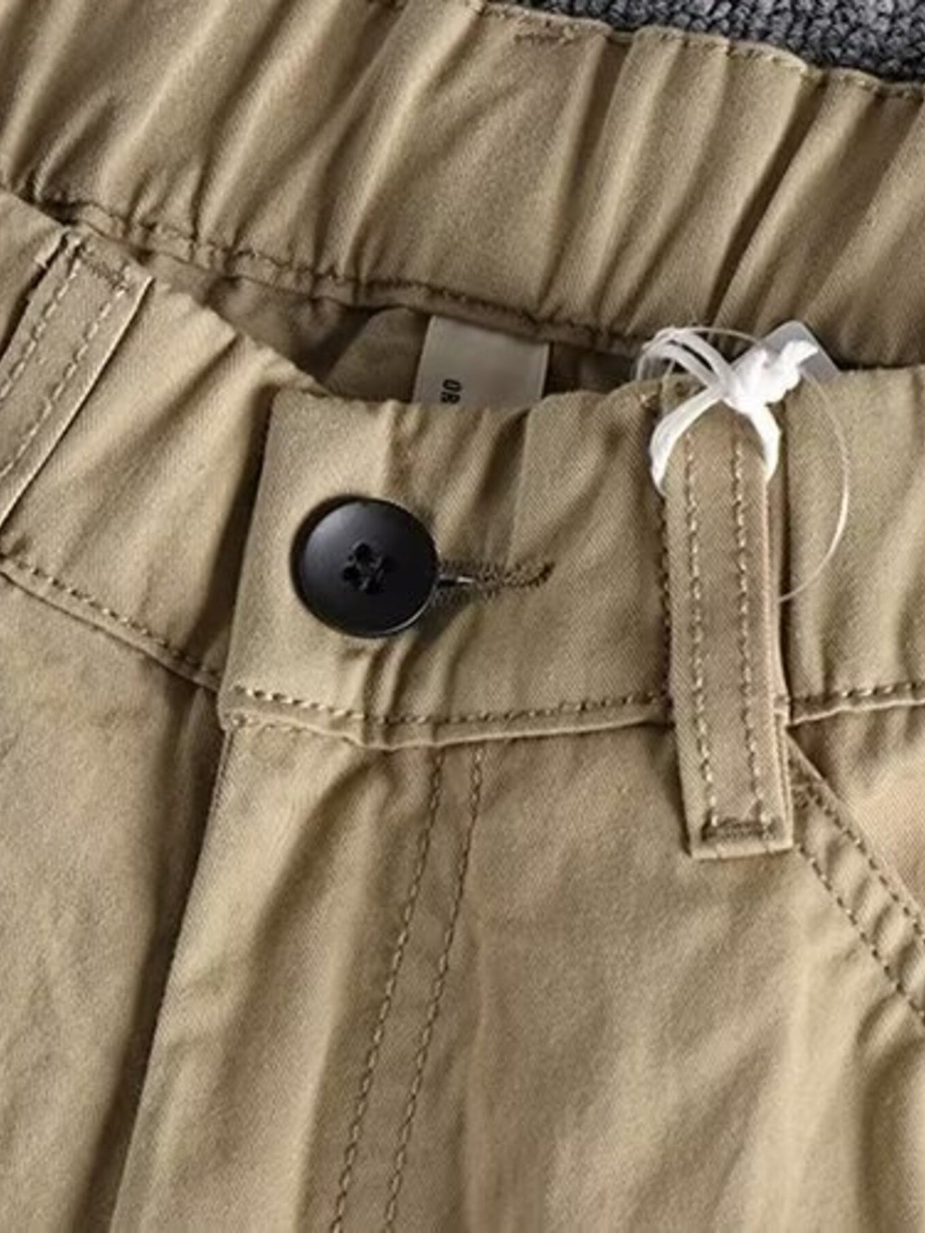 Men's Khaki elastic waist cargo pants with button closure and visible stitching detail.