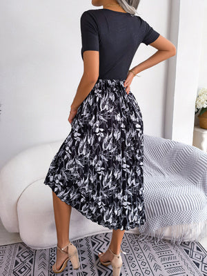Botanical pleated midi dress in black with a white leaf print, featuring a ribbed bodice and short sleeves.