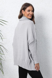 Light gray batwing knit turtleneck sweater with ribbed sleeves and hem.