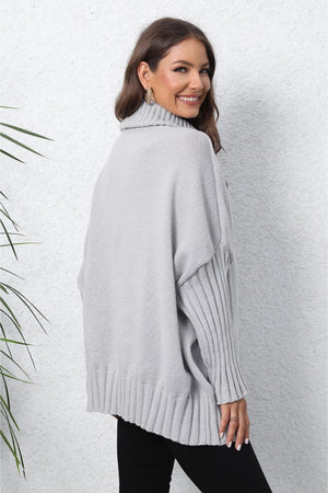 Light gray batwing knit turtleneck sweater with ribbed sleeves and hem.