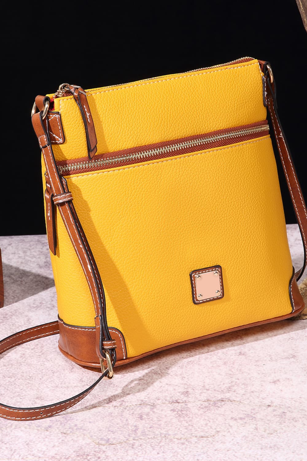 Yellow leather crossbody bag with brown trim and a zippered top compartment.