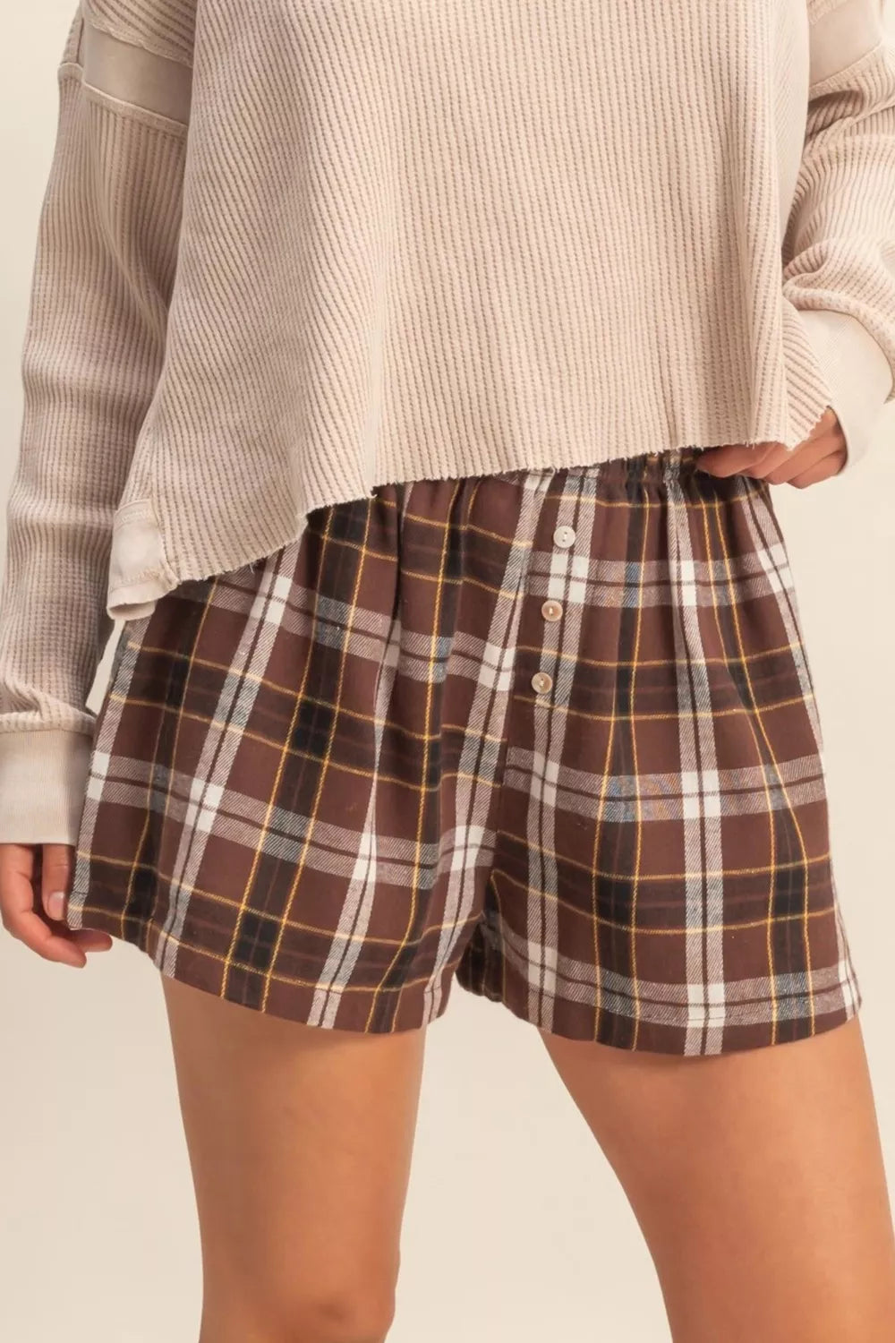 Cozy plaid elastic waist shorts in brown with button detail.