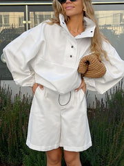 White two-piece set with snap details, featuring a collared pullover top and Bermuda shorts.