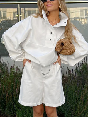 White two-piece set with snap details, featuring a collared pullover top and Bermuda shorts.
