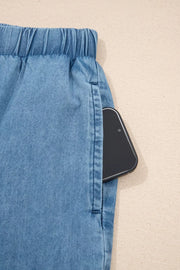Maternity wide-leg chambray jeans in light blue denim with an elastic waistband and a phone in the pocket.