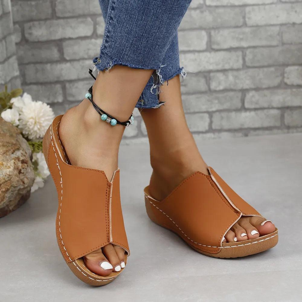 Caramel vegan leather asymmetrical slides with white stitching detail.