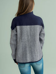 Chevron knit turtleneck sweater in dark blue and white herringbone pattern.