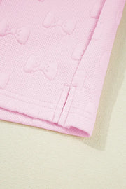 Blush pink loungewear set with embossed bow pattern and ruffle sleeve detail.