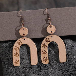 Wooden arch earrings in camel with engraved paw prints and copper hooks.