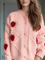 Pink knit cardigan with strawberry appliques and pearl buttons.
