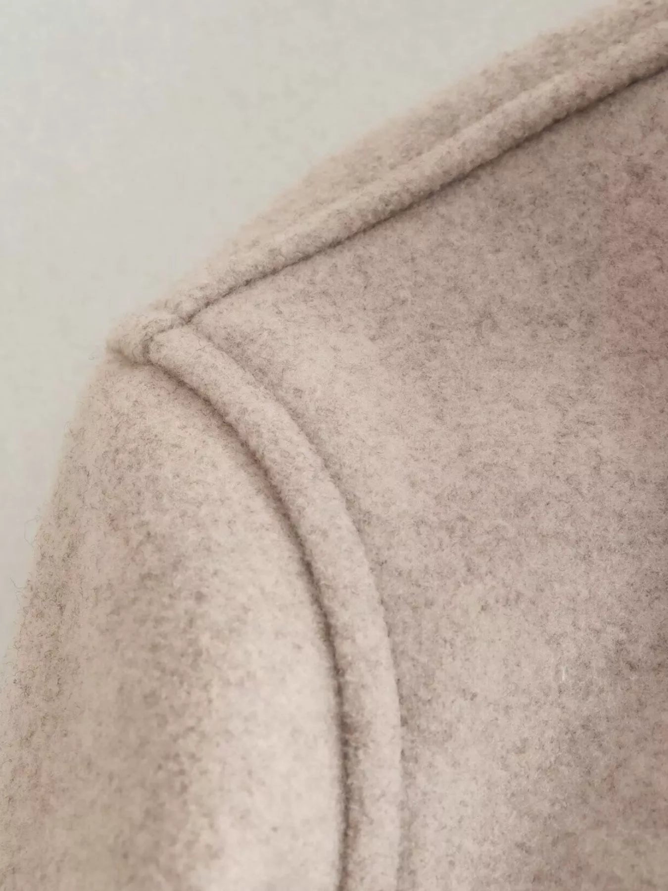 Beige trucker jacket detail showing seam and textured fabric